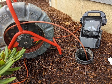 A sewer line inspection is being performed at the entry point of the system to illustrate home inspection services.